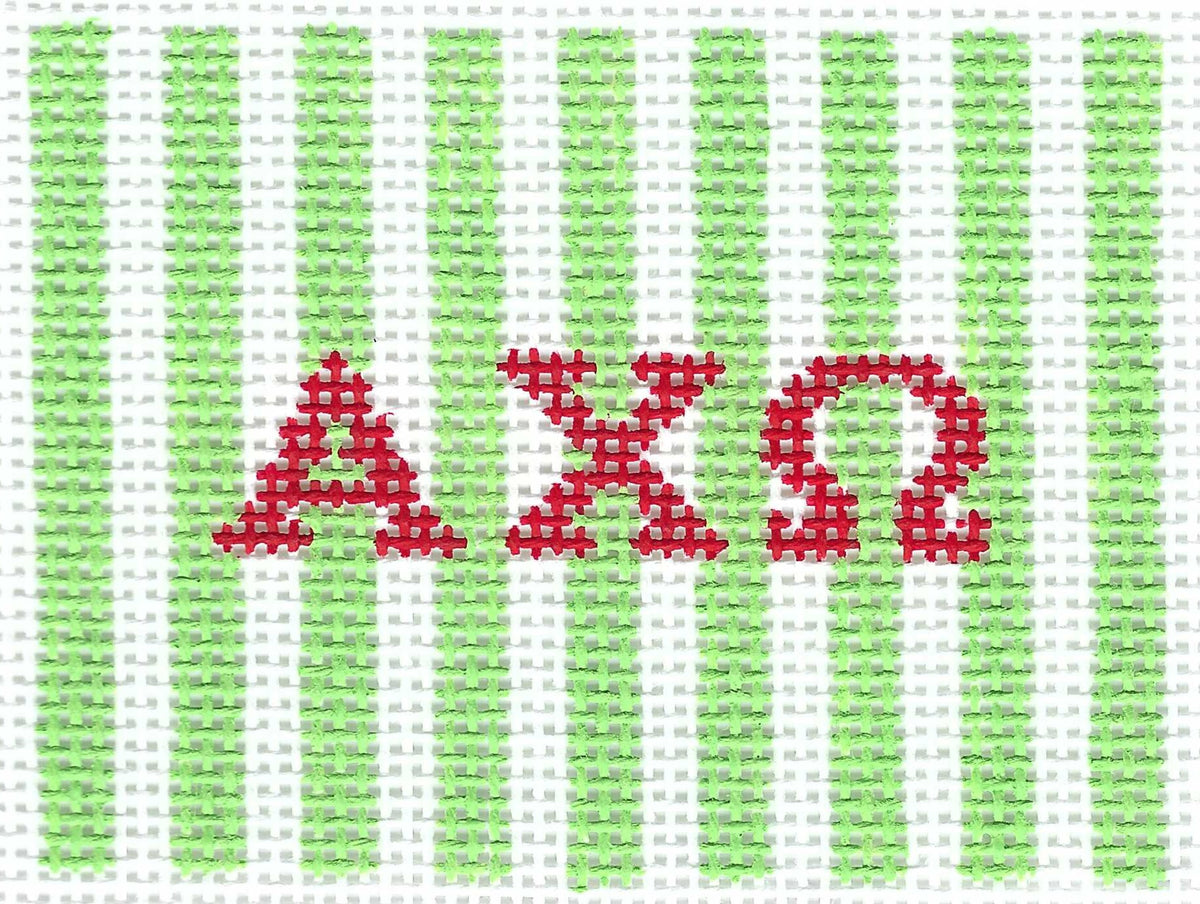 A needlepoint canvas featuring light green and white vertical stripes with the Greek letters Alpha, Chi, and Omega stitched in red across the center.