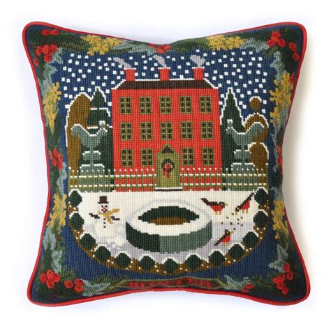 Elizabeth Bradley cross stitch tapestry kit of a winter scene at a large red home with fence and a snowman in front yard with a holly-themed border.