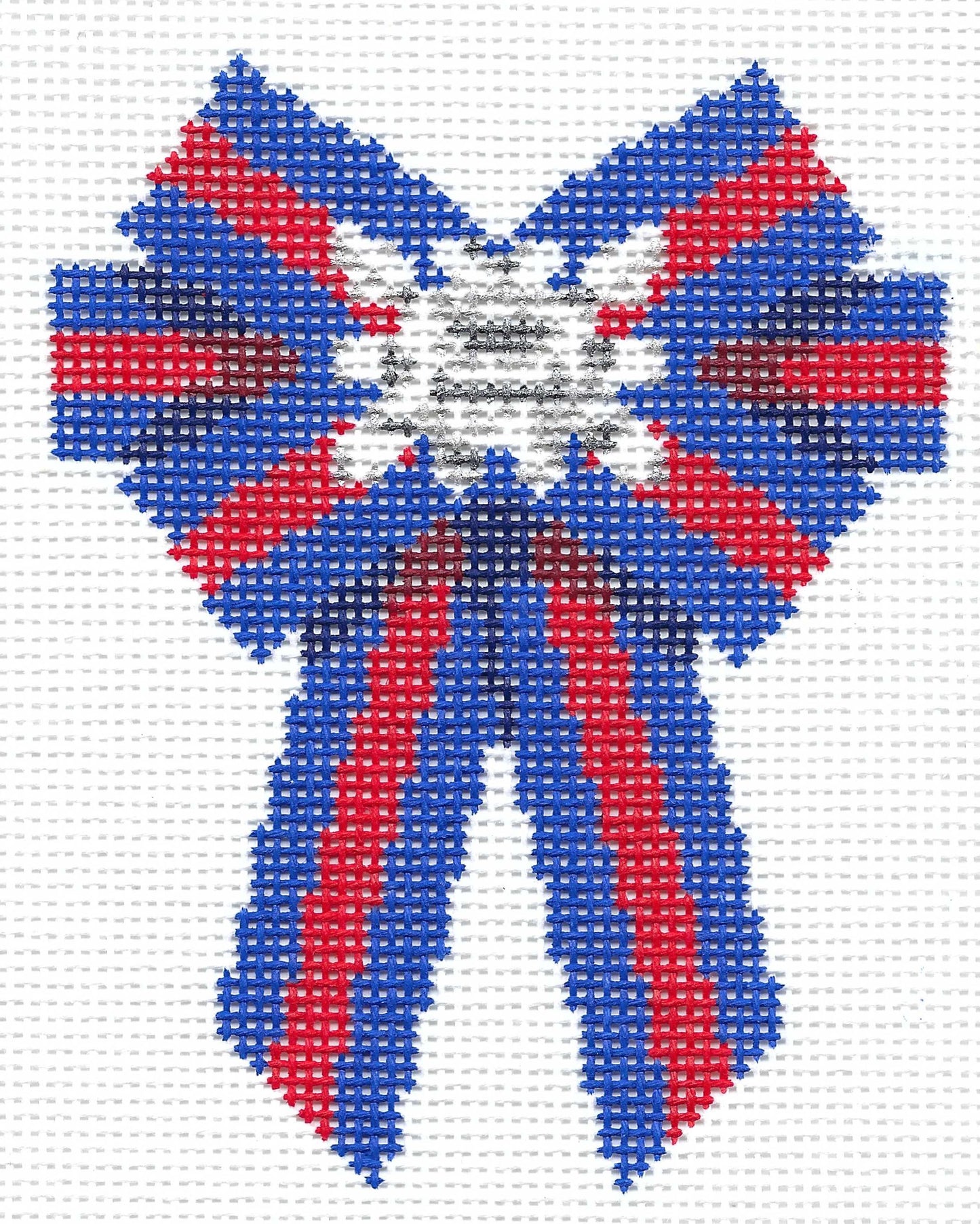 Stitchtent needlepoint canvas of a British bow decorated with a brooch, featuring blue, red, and white colors on a white grid background.