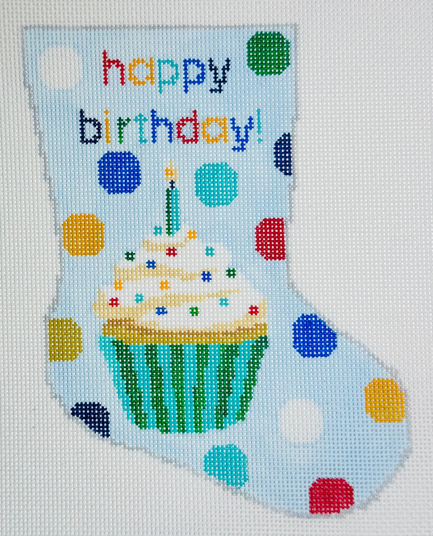 KCN Designers needlepoint canvas of Bauble Stocking with a birthday cupcake design and 'happy birthday!' text on a light blue background with colorful polka dots.
