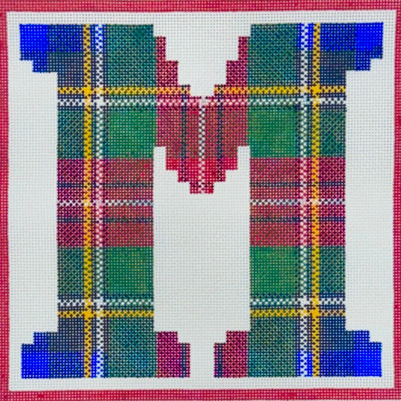 Treglown square needlepoint canvas featuring the letter 'M' filled with a tartan plaid pattern in green, red, blue, yellow, and white, bordered by a red grid.