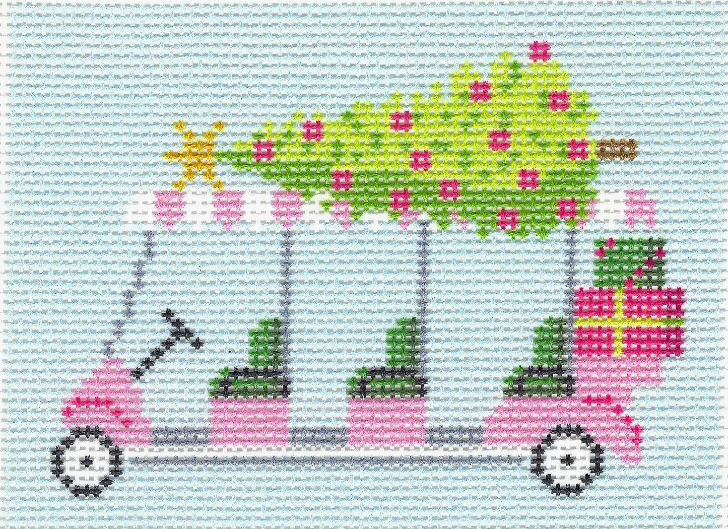 Needlepoint To Go needlepoint canvas of a pink golf cart carrying a green Christmas tree with pink ornaments, plus wrapped gifts on the back, set against a light blue stitched background.