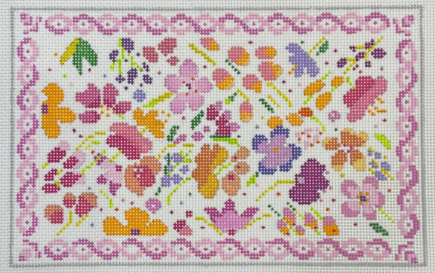Needlepoint canvas of a preppy floral pattern with colorful flowers and a pink border.