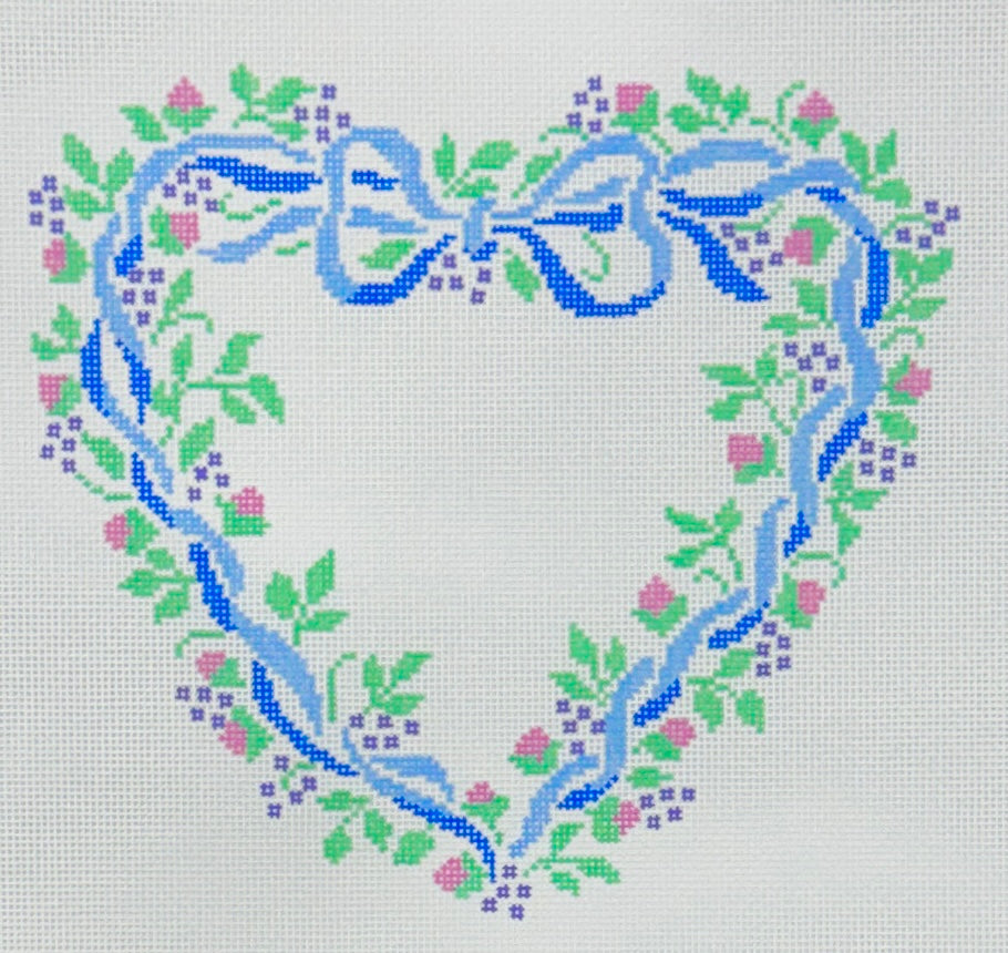 Treglown needlepoint canvas of a heart-shaped floral wreath design on a white background, featuring a blue ribbon bow at the top, green leaves, pink flowers, and small purple blossoms.