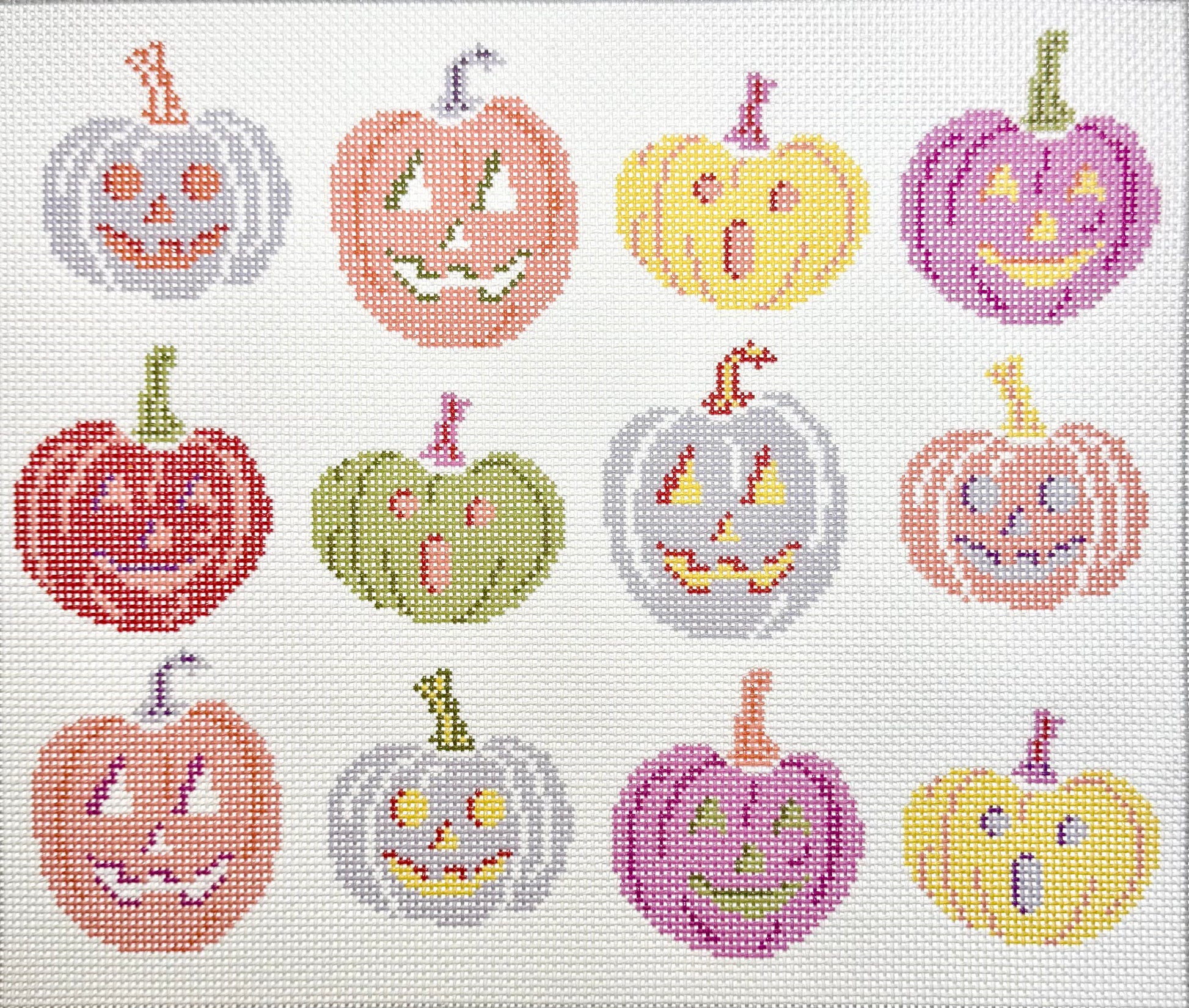 KCN Designers needlepoint canvas of 12 colorful jack-o'-lanterns with smiling and shocked faces on a white background