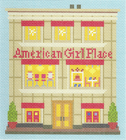 Haus of Toots needlepoint canvas of a storefront illustration labeled 'American Girl Place' on a light blue background, with a beige building facade, red awnings, yellow windows, and small green trees at the base.