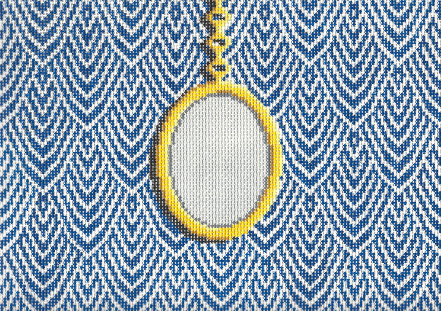 Jeni Sandberg needlepoint canvas of clutch with gold pendant on a white and blue patterned background