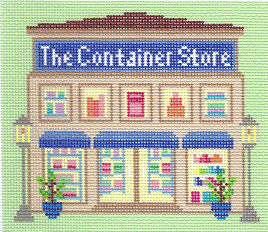 Haus of Toots needlepoint canvas design of a storefront reading "The Container Store" on a light green background, with beige building details, blue awnings and sign, colorful windows, and potted plants.