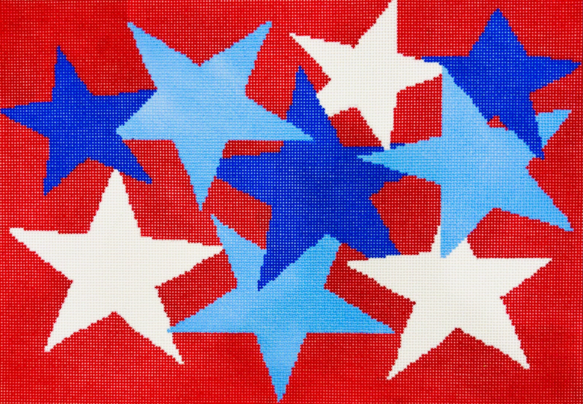 A Stitch in Time needlepoint canvas of white and light and dark blue stars on a red background