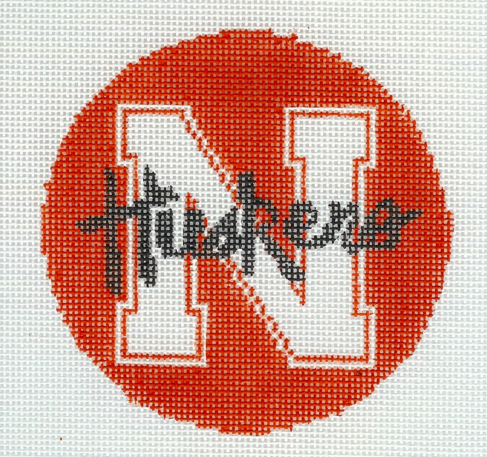 Kathy Schenkel round needlepoint canvas of big white 'N' and 'Huskers' black text with a red background