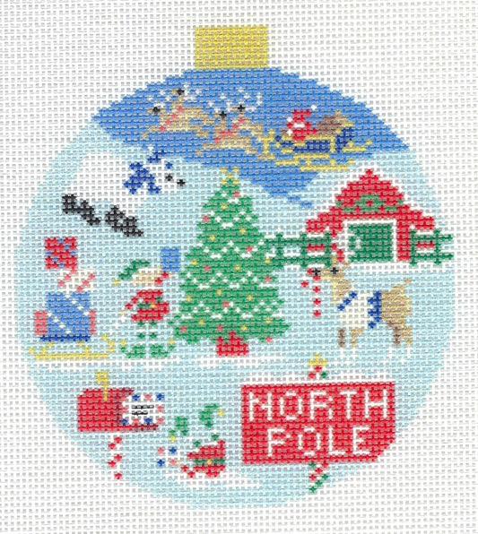Kirk & Bradley round needlepoint design of a North Pole holiday scene featuring Santa in a sleigh, snowman, Christmas tree, reindeer, a red house, candy canes, and a red 'NORTH POLE' sign.