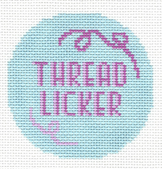 Cece & The Bug circular needlepoint canvas featuring the words 'THREAD LICKER' in pink lettering with a light blue background with pink decorative swirls.