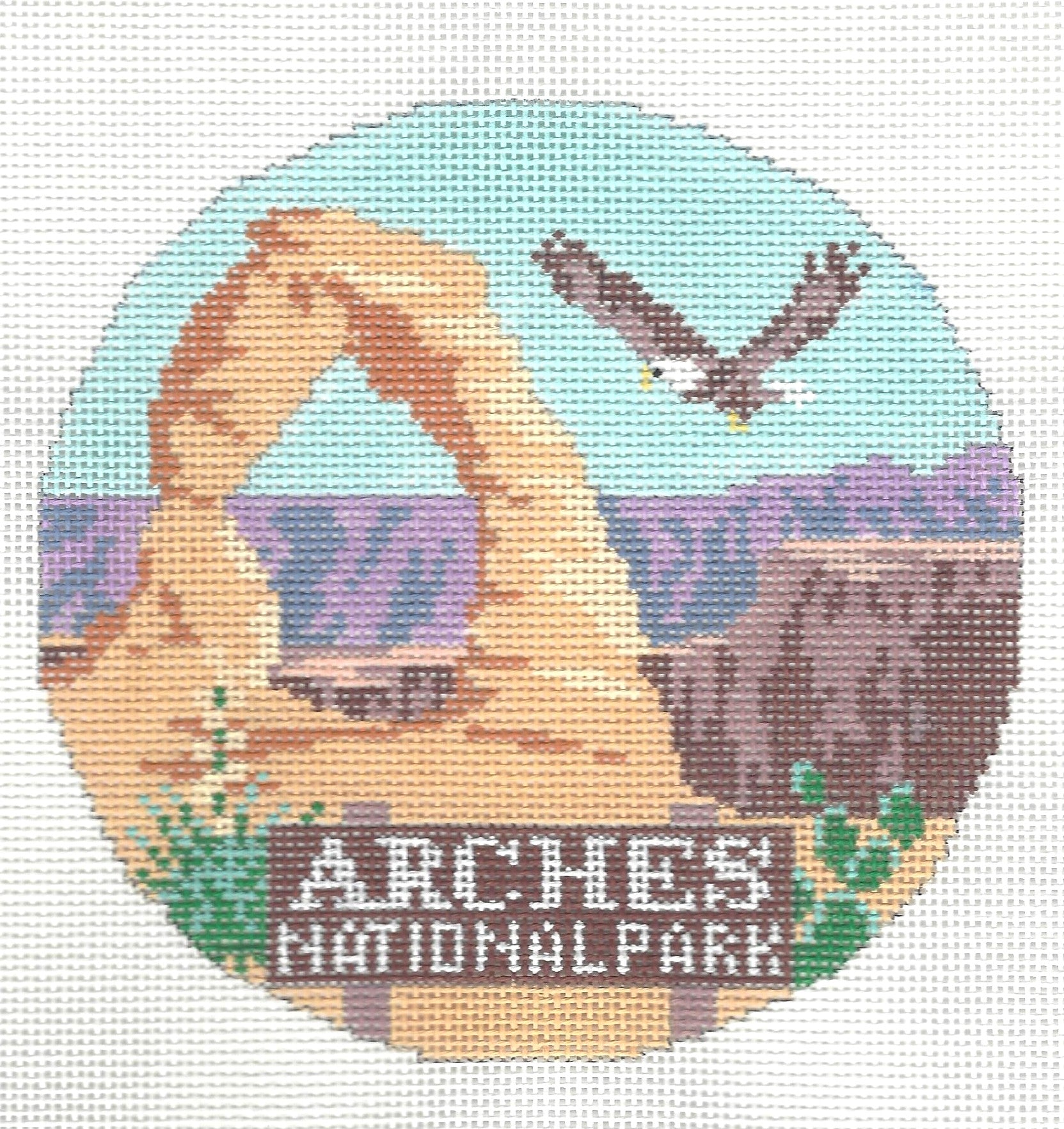 Kirk & Bradley round needlepoint or cross-stitch design of Arches National Park with a natural landscape and eagle.
