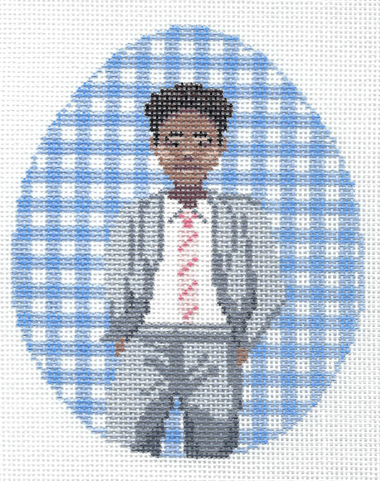 Spellbound Stitchery needlepoint canvas featuring a portrait of a young man with dark hair, wearing a gray suit, white shirt, and pink striped tie, set against a blue and white gingham oval-shaped background.
