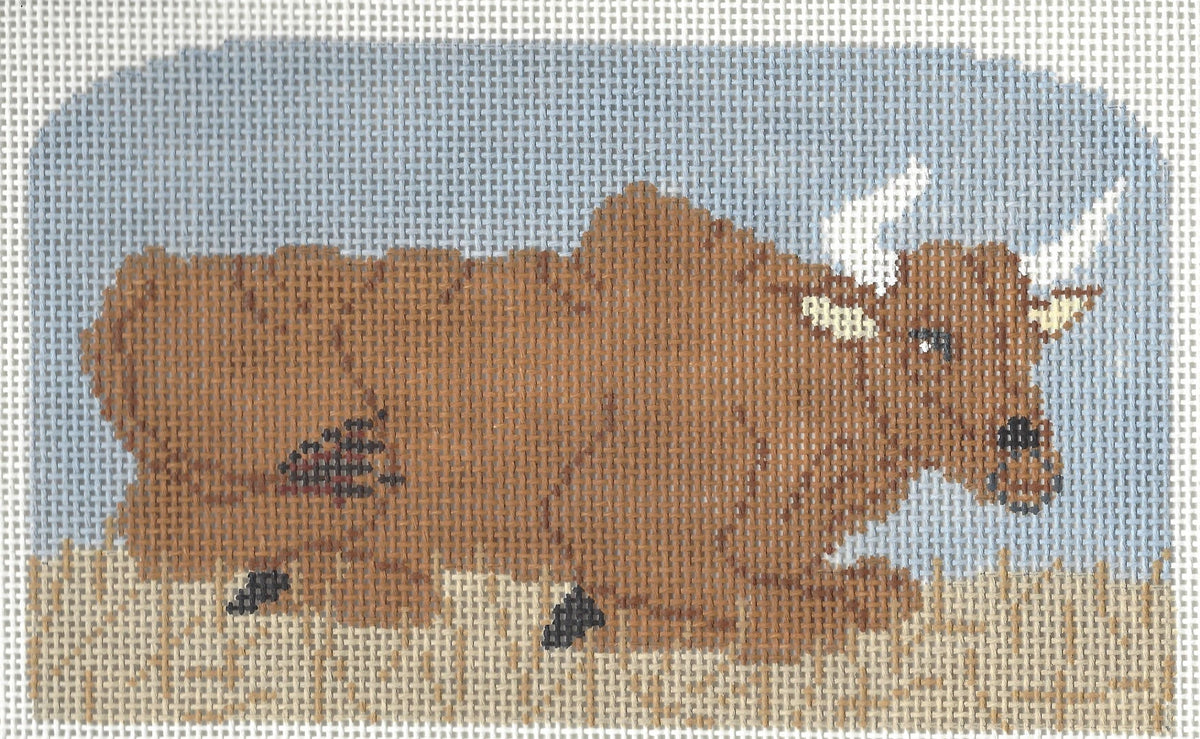 The Collection needlepoint canvas of a brown ox with white horns laying down in brown grass with a blue background.