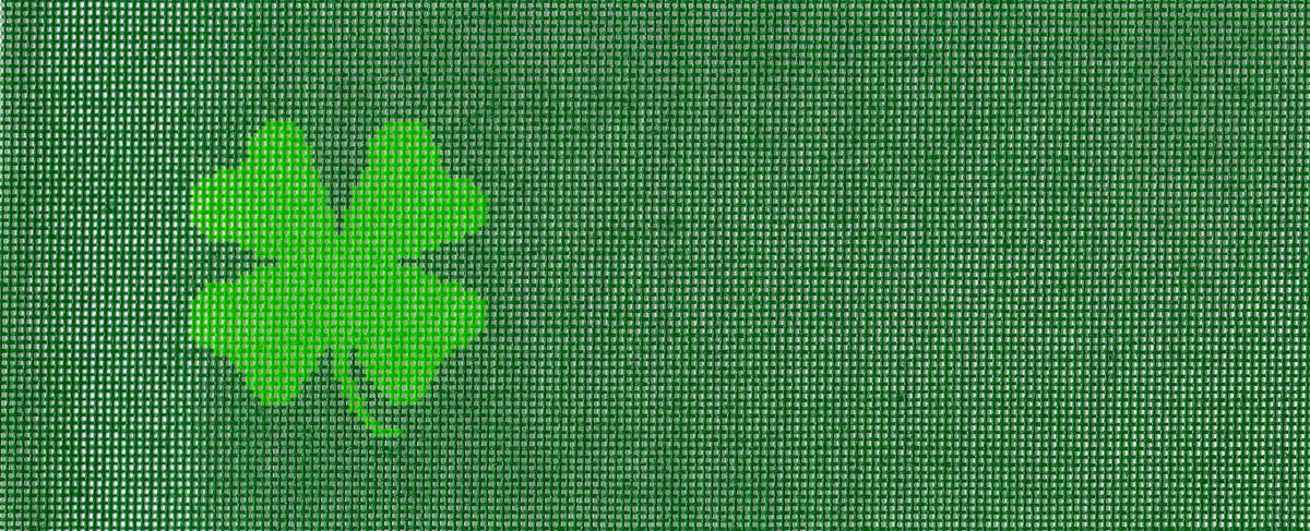 Needlepaint needlepoint canvas of a green four-leaf clover icon on a dark green background.