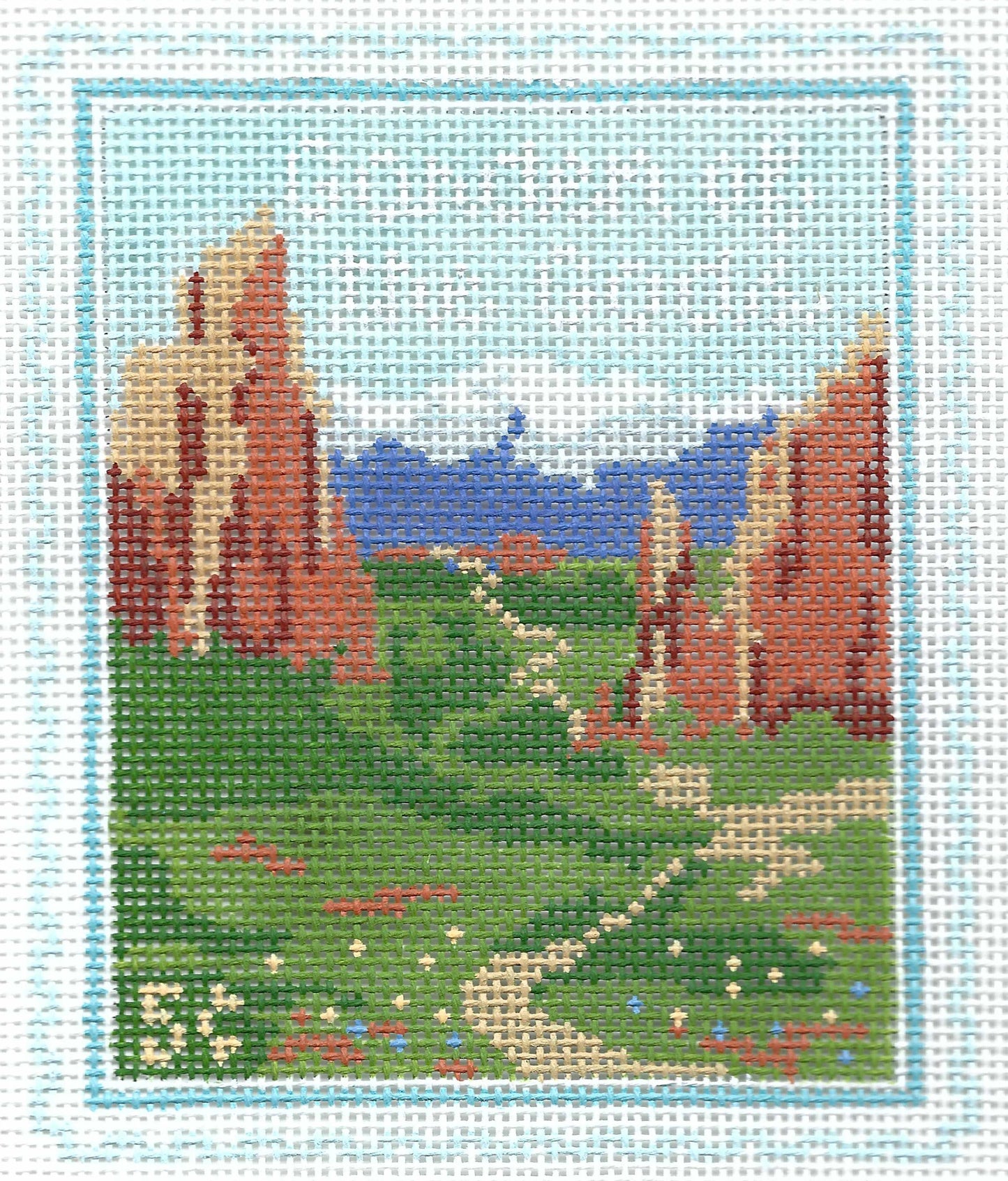 Stitch Style travel stamp needlepoint canvas of Garden of the Gods landscape with red rock formations, greenery, and snow-capped mountains in background.