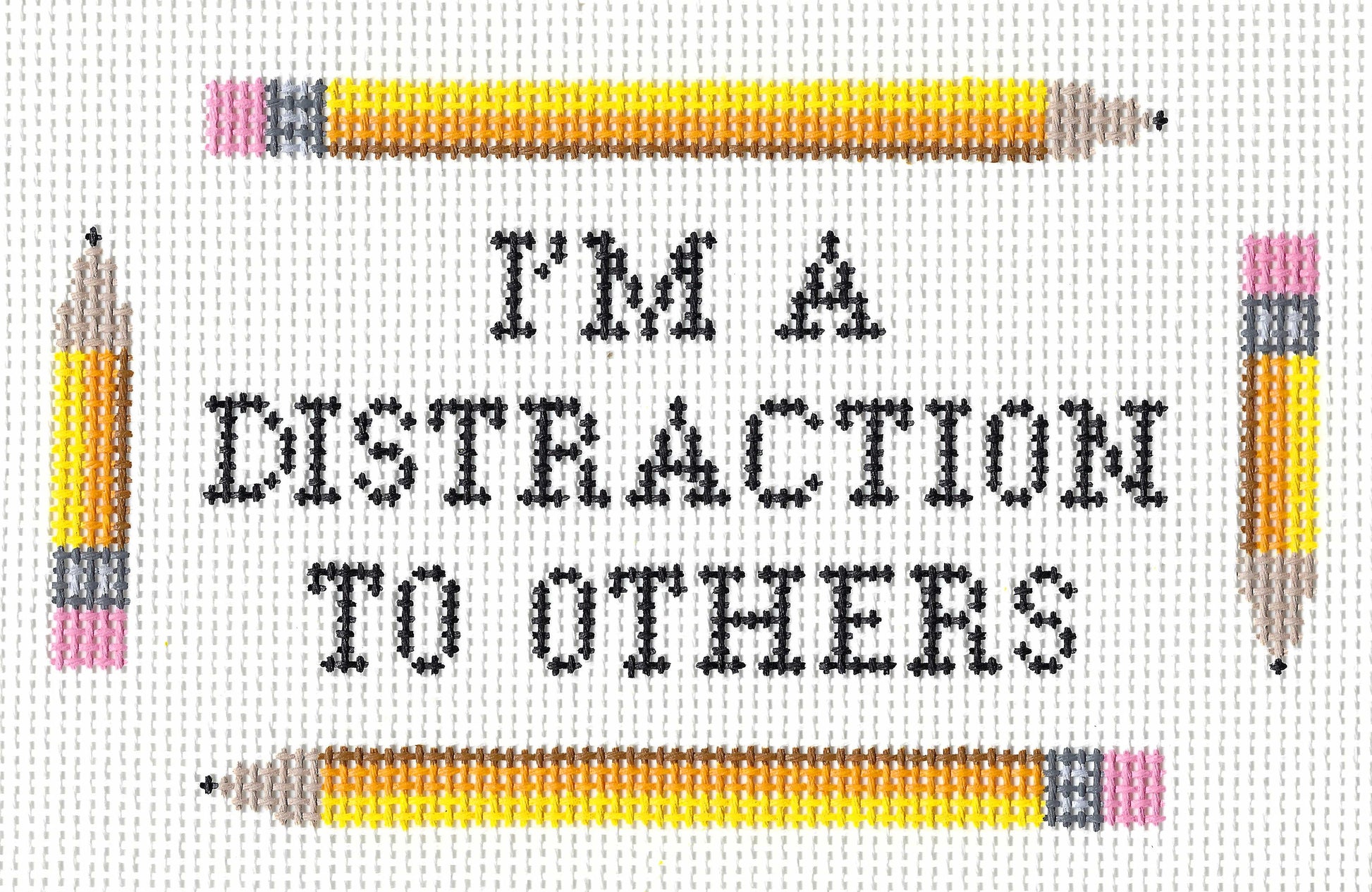 Stitchtent needlepoint canvas of text 'I'M A DISTRACTION TO OTHERS' in black lettering, framed by two yellow pencils at the top and two at the sides on a white background.
