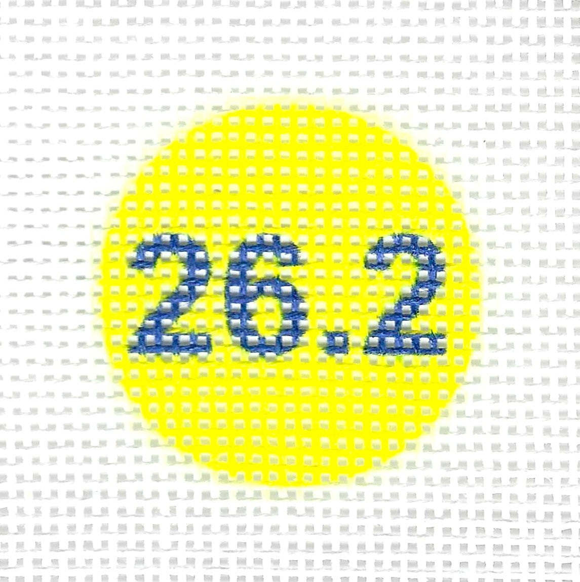 Tilli Tomas Planet Earth circular needlepoint canvas with the blue numbers '26.2' centered on it, set against a yellow background.
