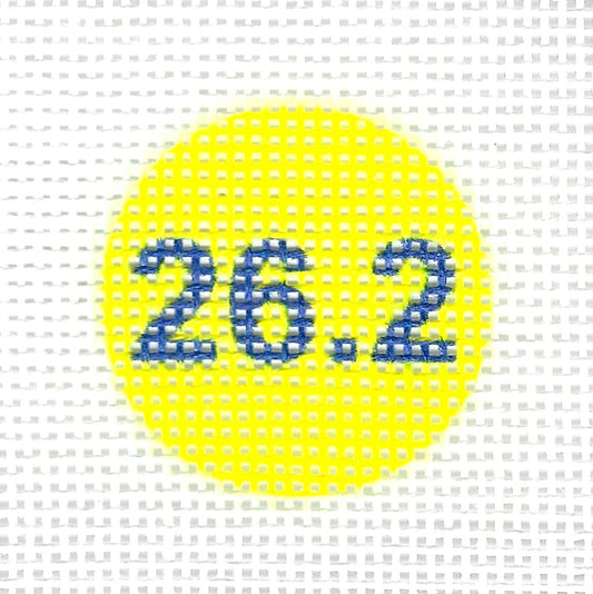 Tilli Tomas Planet Earth circular needlepoint canvas with the blue numbers '26.2' centered on it, set against a yellow background.