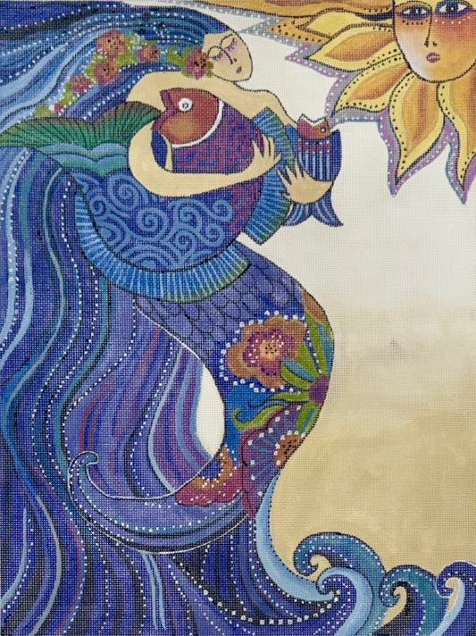 Danji Designs Laurel Burch needlepoint canvas with stylized artwork showing a woman with flowing blue and purple hair, holding two fish, with a sun face in the upper right on a cream background.