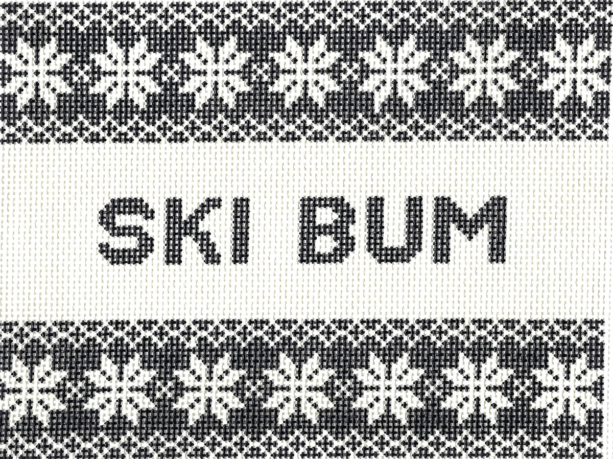 Saturnalia Stitching needlepoint canvas of a knitted textile pattern with black and white Nordic snowflake motifs and the words 'SKI BUM' centered on a white band.