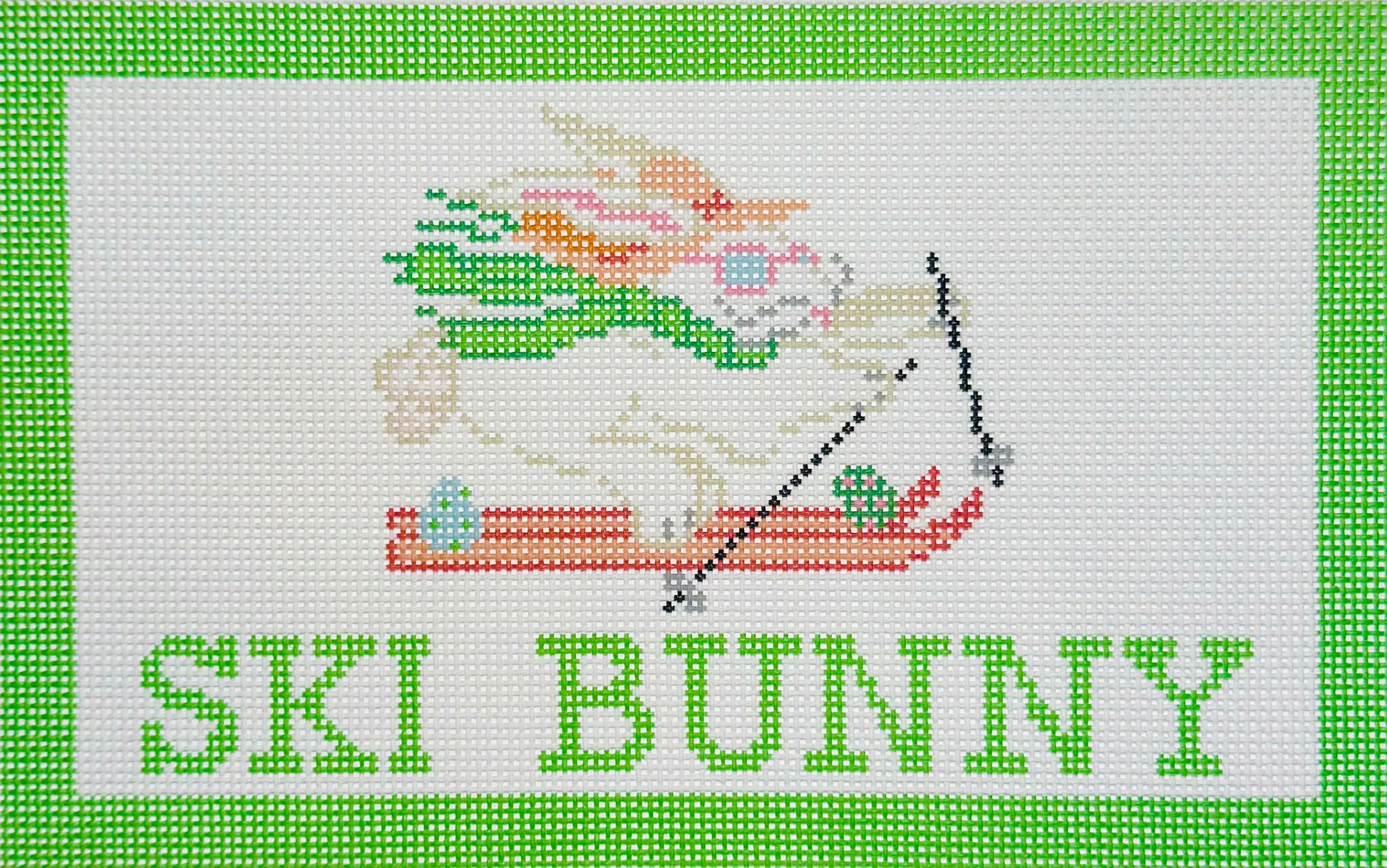 KCN Designers needlepoint canvas of a bunny skiing with 'SKI BUNNY' text on a white background and a light green border.