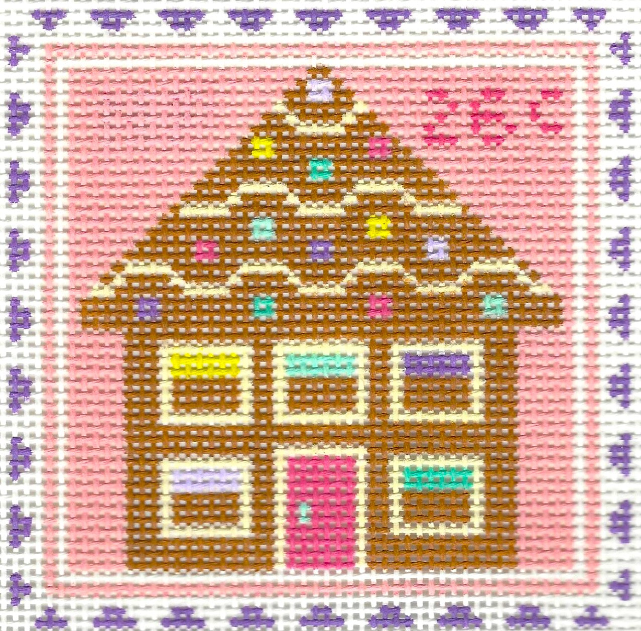 Stitch Rock needlepoint canvas of a colorful gingerbread house with a pink background and a white and purple border