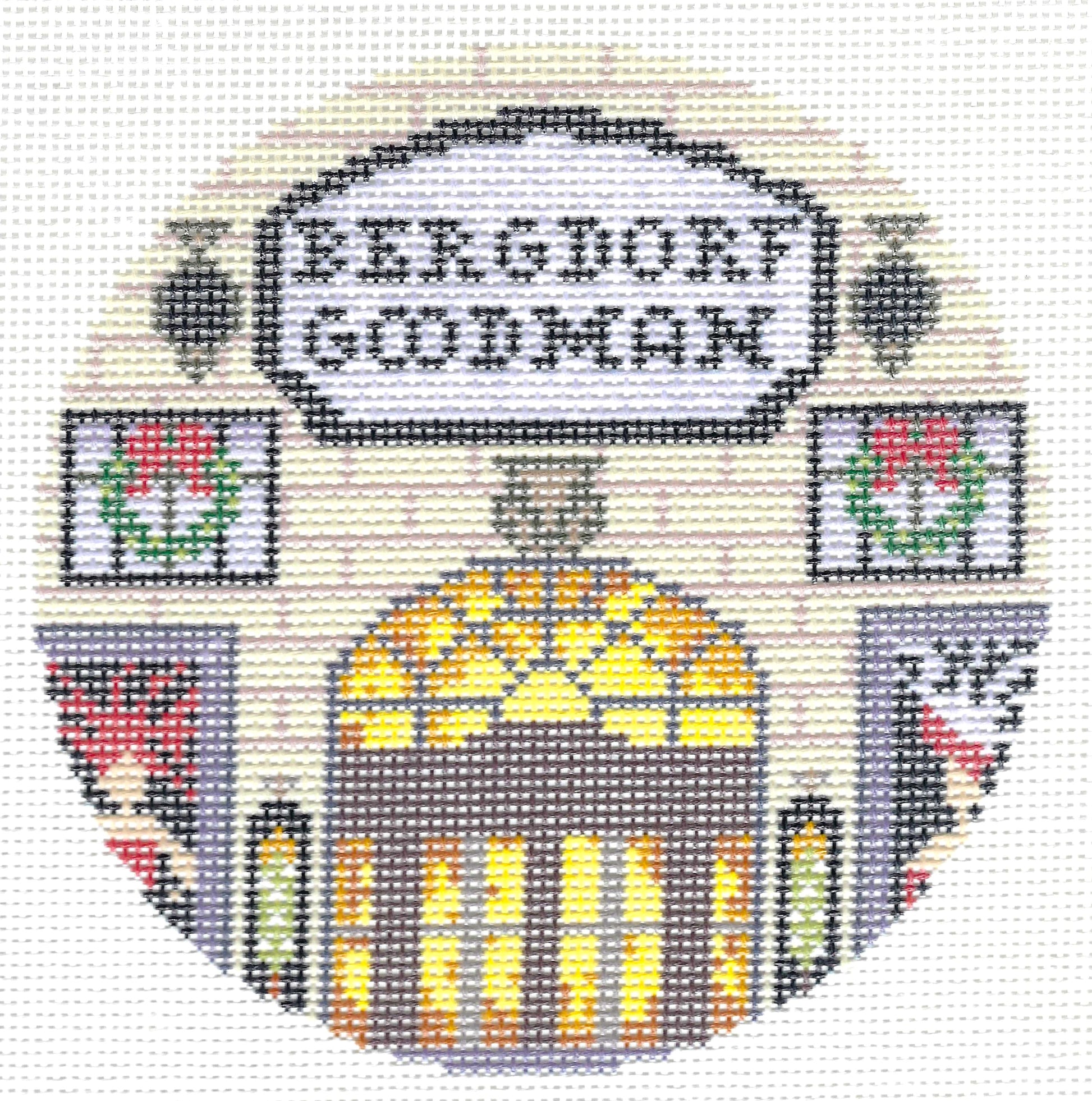 Gingham Stitchery circular needlepoint canvas featuring the words 'BERGDORF GOODMAN' in a white sign above an arched doorway with yellow and orange window light, flanked by floral panels and gray side sections on a light background.