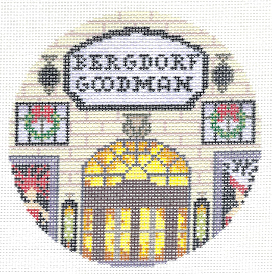 Gingham Stitchery circular needlepoint canvas featuring the words 'BERGDORF GOODMAN' in a white sign above an arched doorway with yellow and orange window light, flanked by floral panels and gray side sections on a light background.