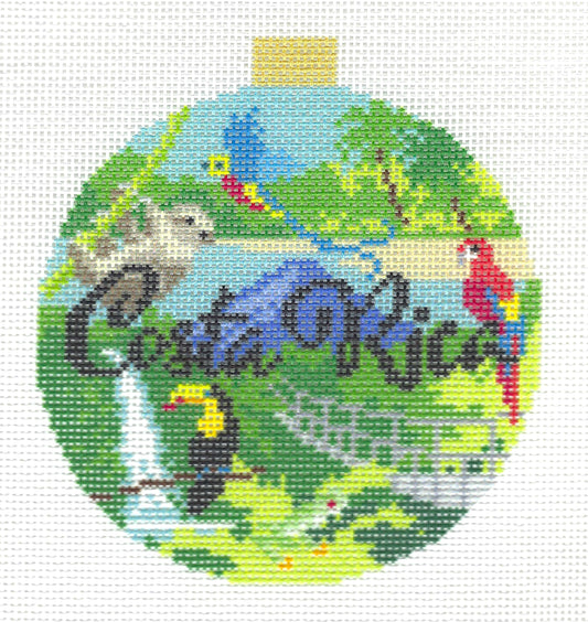 Kirk & Bradley round needlepoint canvas featuring the words 'Costa Rica' in dark script with green foliage, blue water, a red-and-yellow parrot, a toucan, a bird, and a small gold hanging tab at the top.