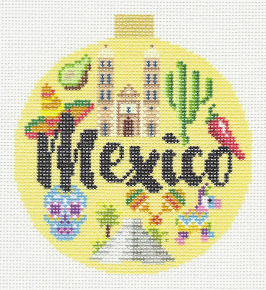 Kirk & Bradley circular needlepoint canvas featuring the word 'Mexico' in black script, surrounded by colorful Mexican-themed motifs including a cactus, sombrero, chili pepper, sugar skull, pyramid, and buildings on a pale yellow background.