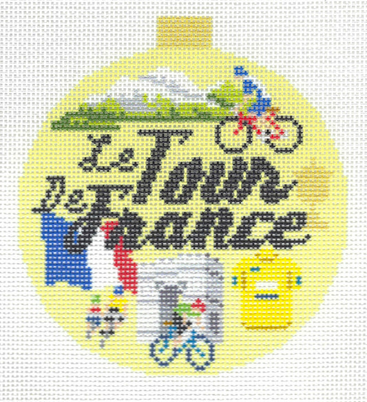 Kirk & Bradley round needlepoint canvas of text 'Le Tour De France' with cycling, mountain scenery, the French flag, a cyclist, a building, and a yellow jersey on a light yellow background.