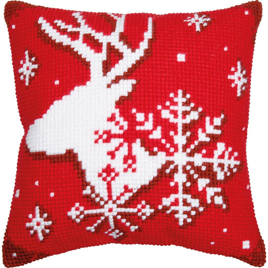 A square red and white needlepoint pillow featuring a white reindeer silhouette and large white snowflakes on a red background.