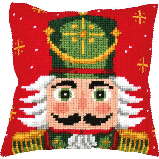 Vervaco DIY kit of a square red Christmas nutcracker pillow featuring a colorful design of a festive soldier with a green hat, black mustache, and gold trim on a red background.